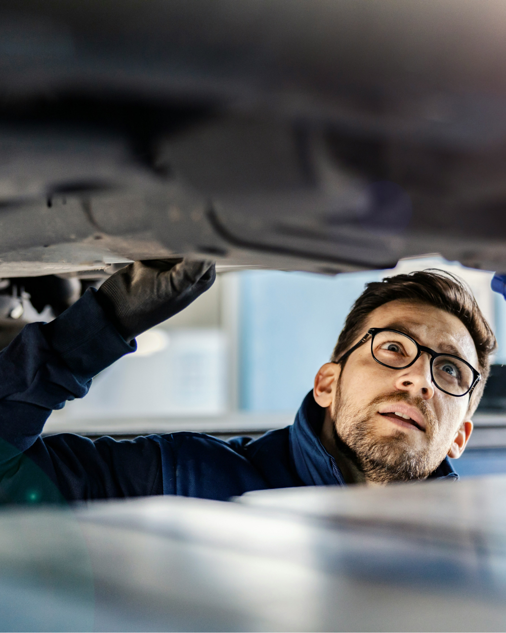 Close-up of a man inspecting the underside of a car.