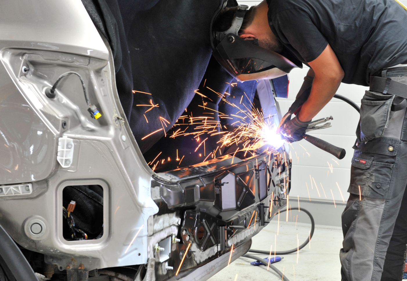 Close-up of a man welding the rear of a car.