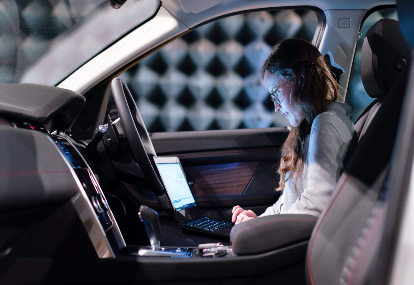 Bild på en mdelålderskvinna som sitter i passagerarsätet med en dator i knät.