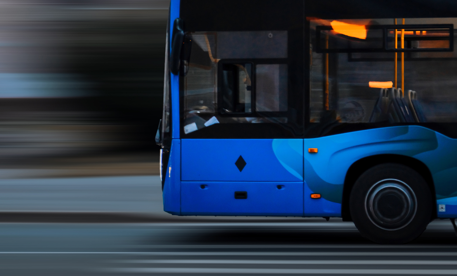Bild på en blå buss fotograferad från sidan med blurrig bakgrund